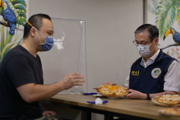 」圖：香港籍新住民Howard(左)向移民署署長鐘景琨(右)介紹「一個人的披薩