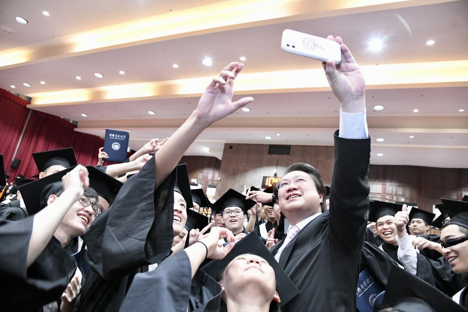 Minister of the Interior Lin Yu-chang taking a selfie with the graduates of CPU