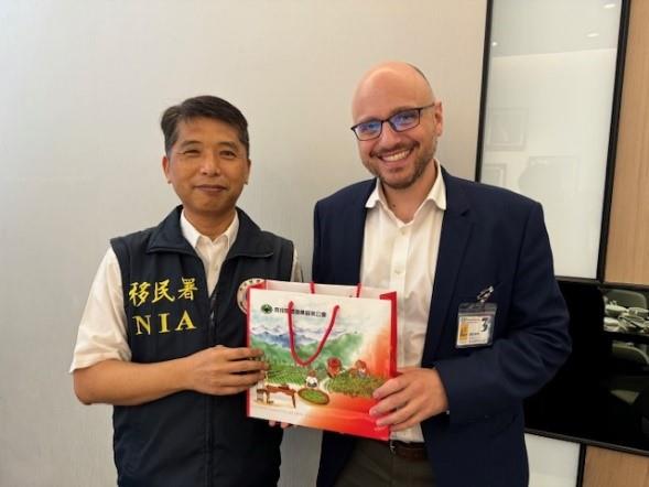 Tsai Yingjie (left), the assistant general commander of NIA's Border Affairs Corps, presents a commemorative gift to Samuel Goffman, the deputy branch director of the Kaohsiung Branch Office of the AIT (right)