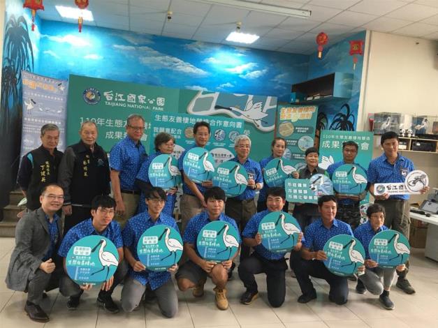 A group photo of fishermen holding identification signs of eco-friendly habitats construction
