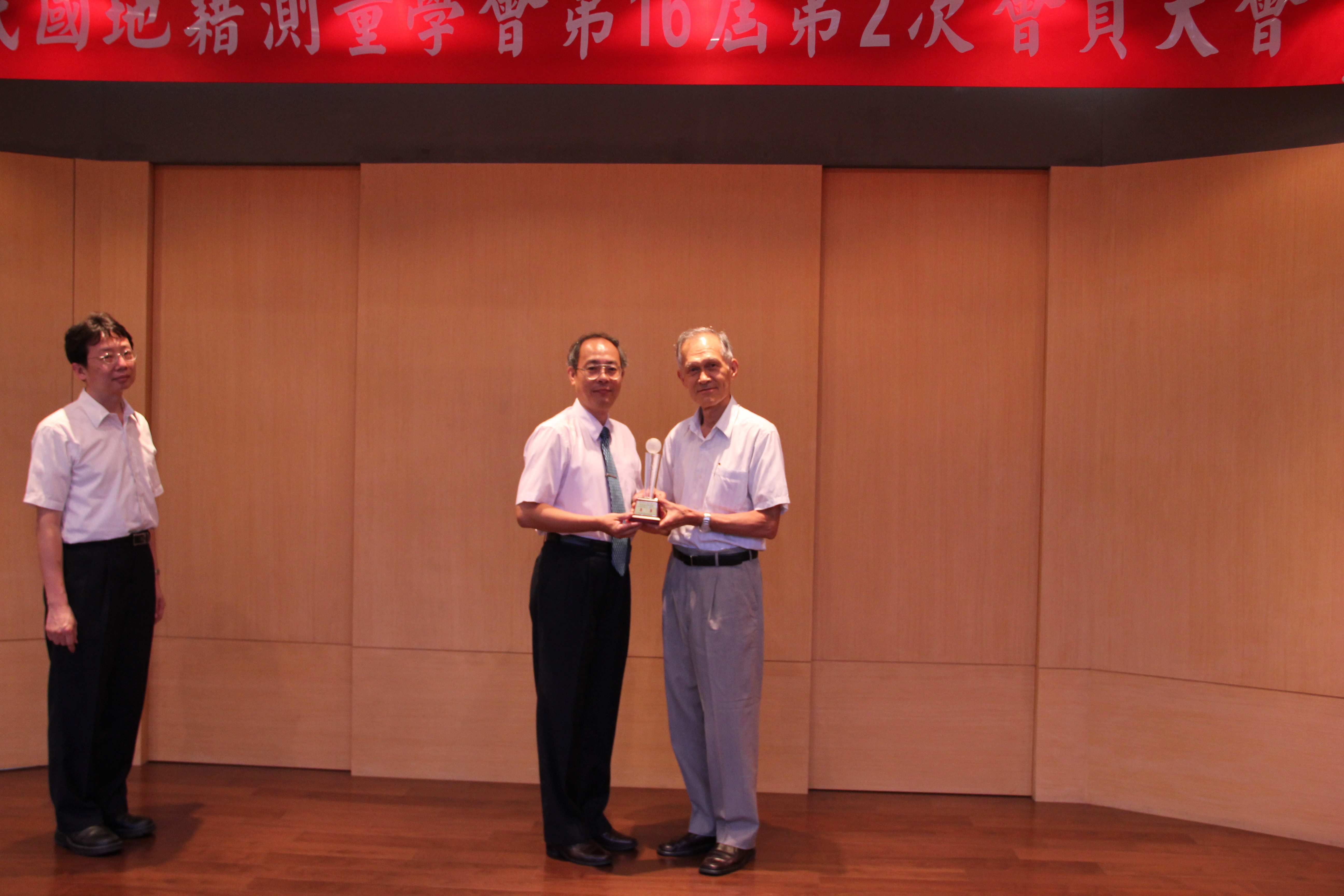 中華民國地籍測量學會曾前理事長德福（右）致贈季軍獎盃予本中心劉主任正倫（左）